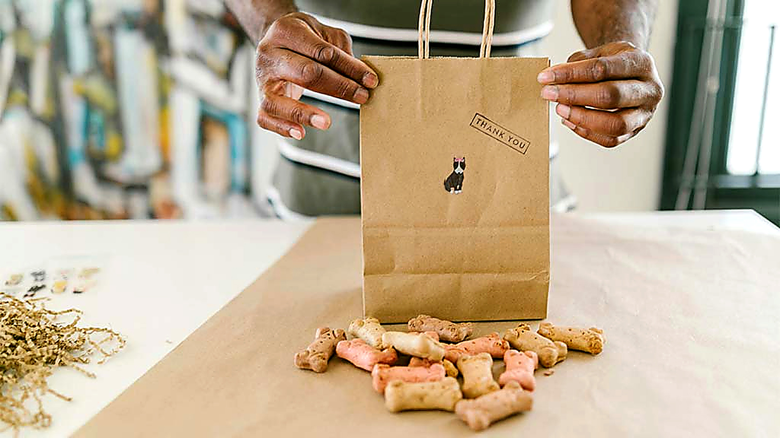 Bone-shaped dog treats displayed beside a kraft paper thank-you bag for pet customers.